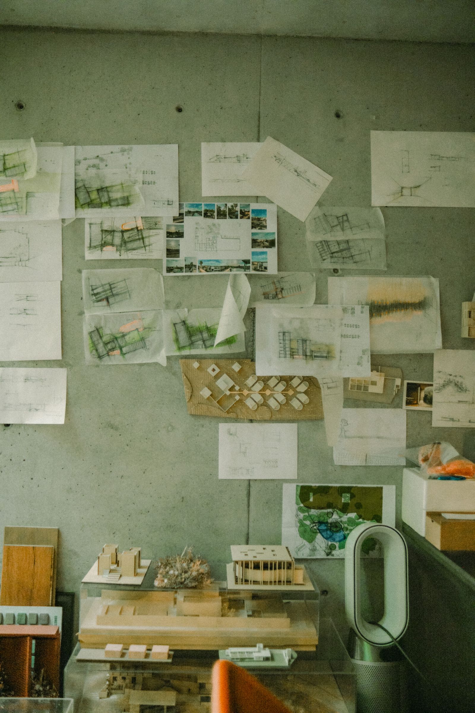 Architectural drawings and models displayed on a studio wall