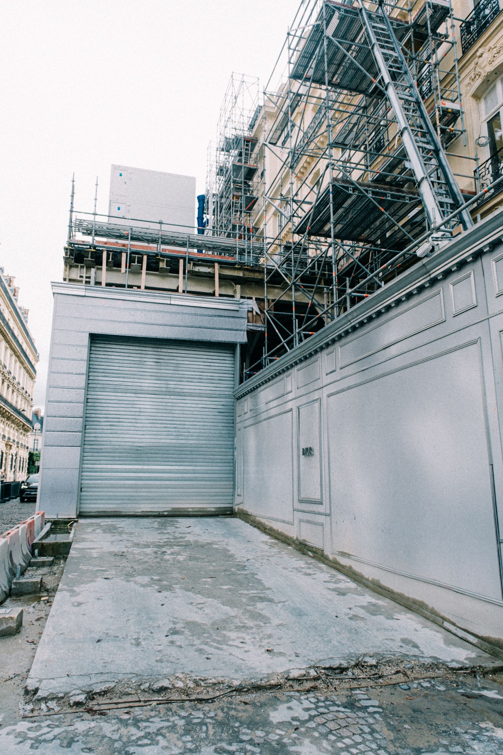 Building facade under construction with scaffolding, a garage opening and exposed work above