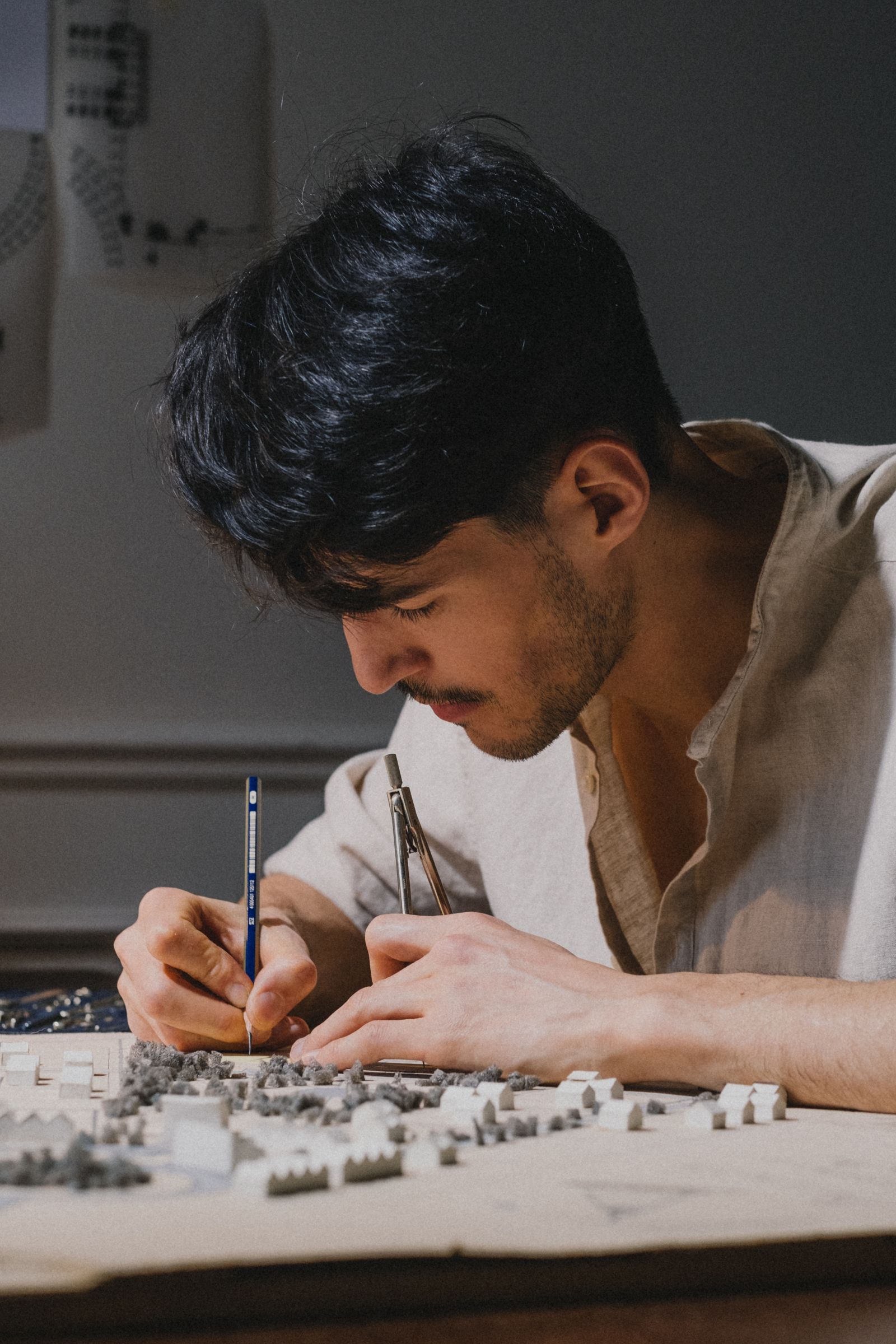 Designer working with a pencil and dividers over a physical site model