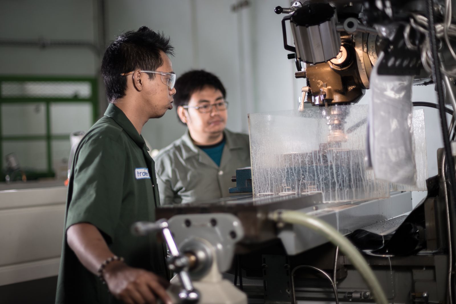 Technicians work beside a CNC machine in a workshop