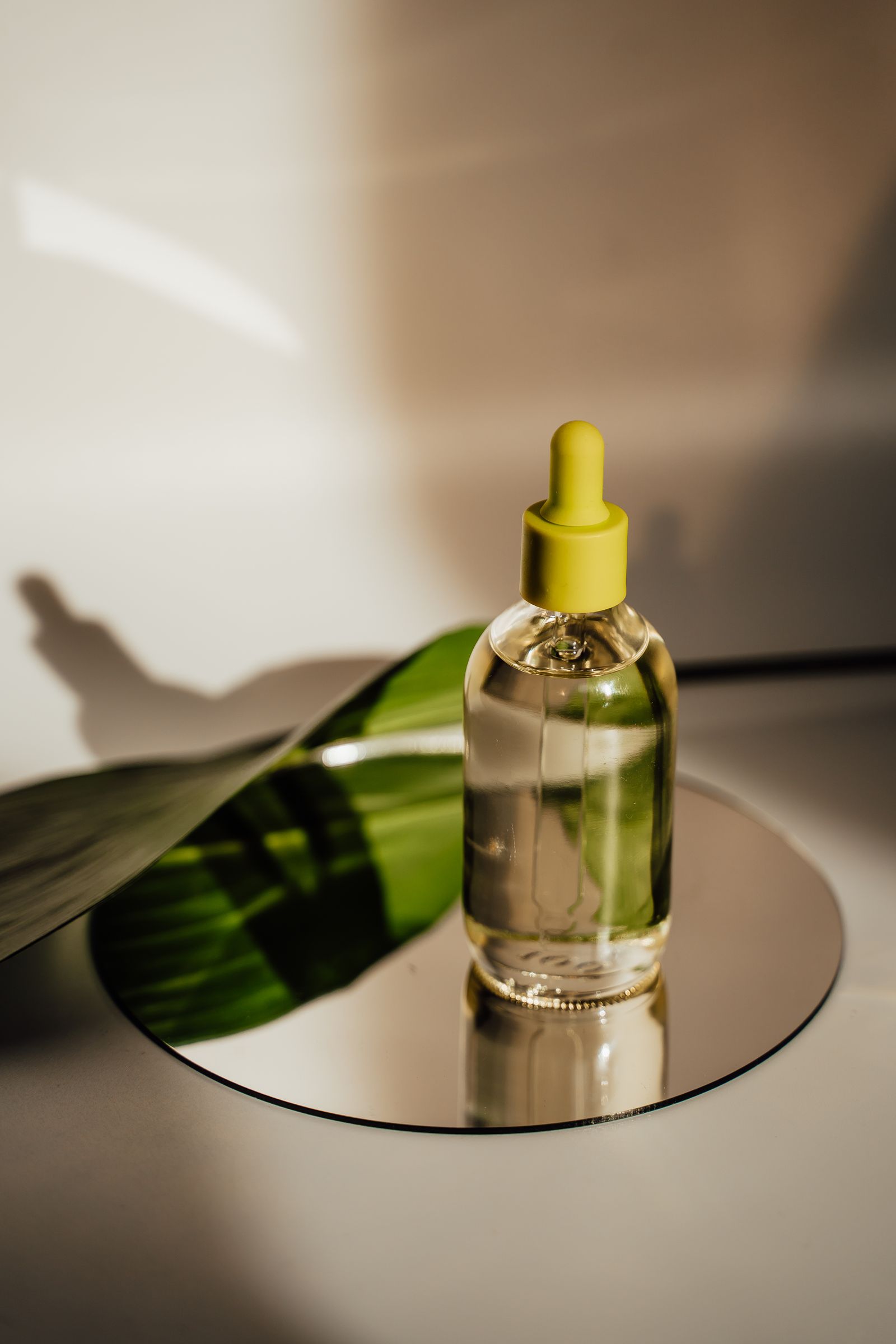 Clear glass dropper bottle on a reflective surface with soft shadows