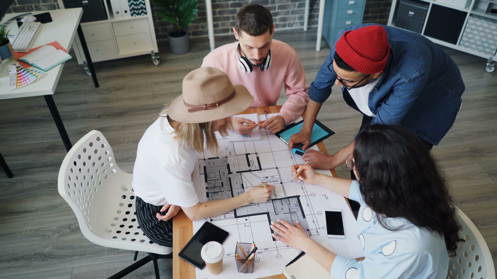 Four people gathered around a table discussing a house drawing