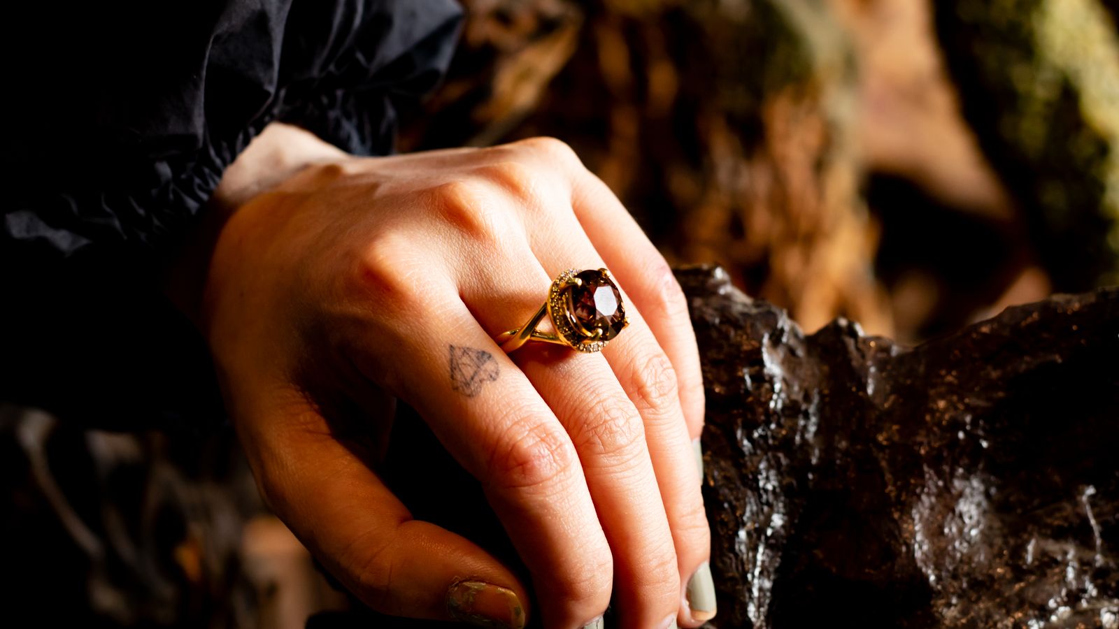 Hand wearing a gold-colored ring with a stone