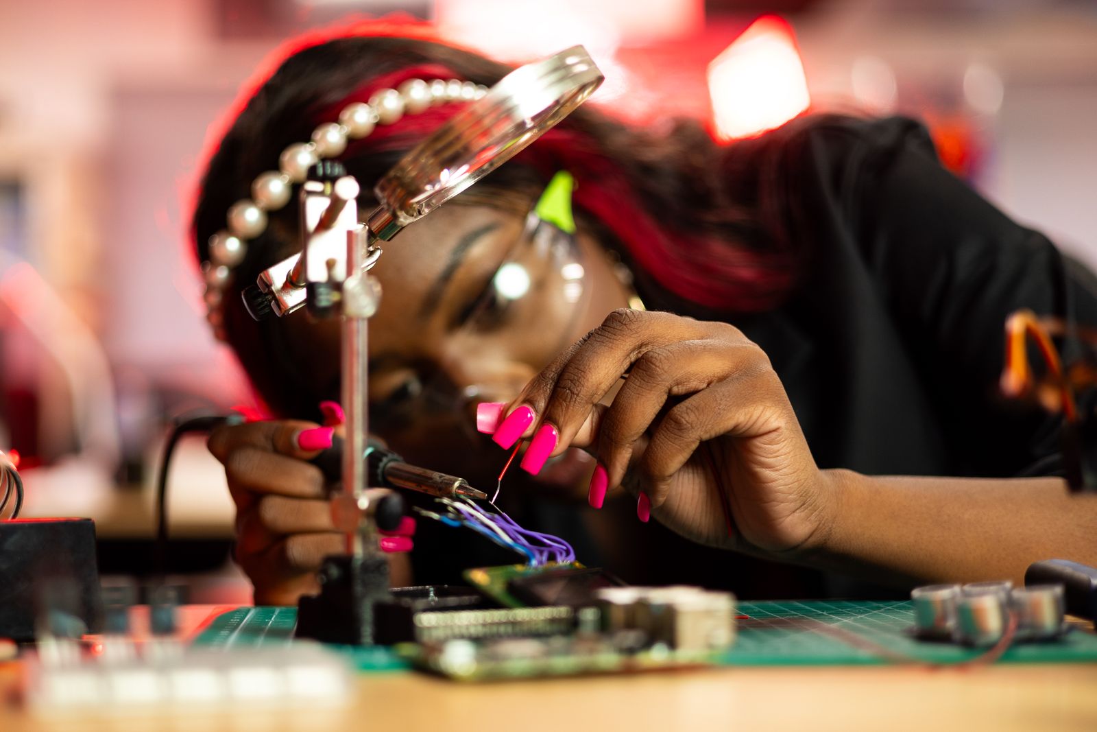 Engineer works on electronics and wiring with a small tool under a magnifying lens
