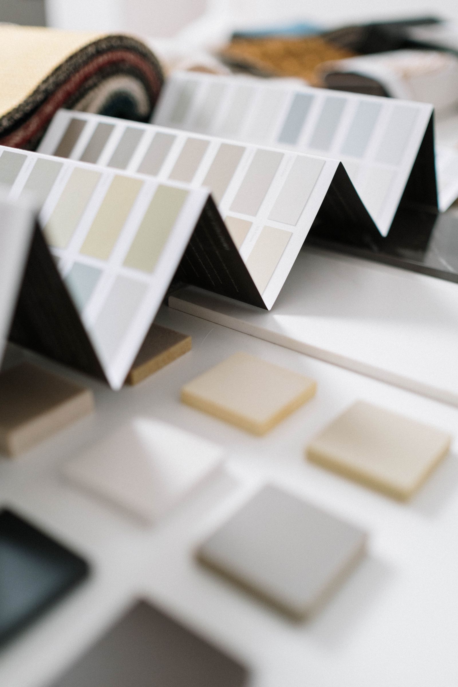 Neutral color swatches stand among fabric and solid material samples on a table