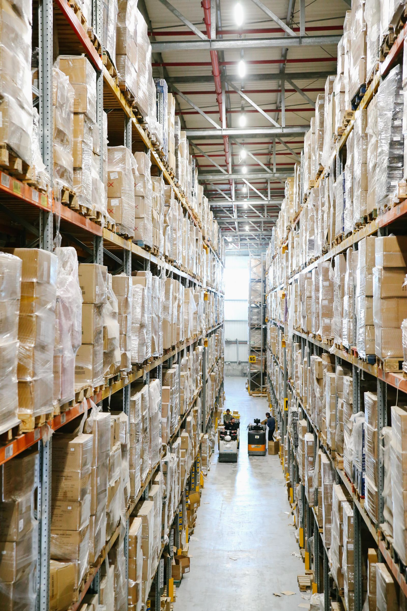 Warehouse shelves hold labeled cardboard boxes along an aisle