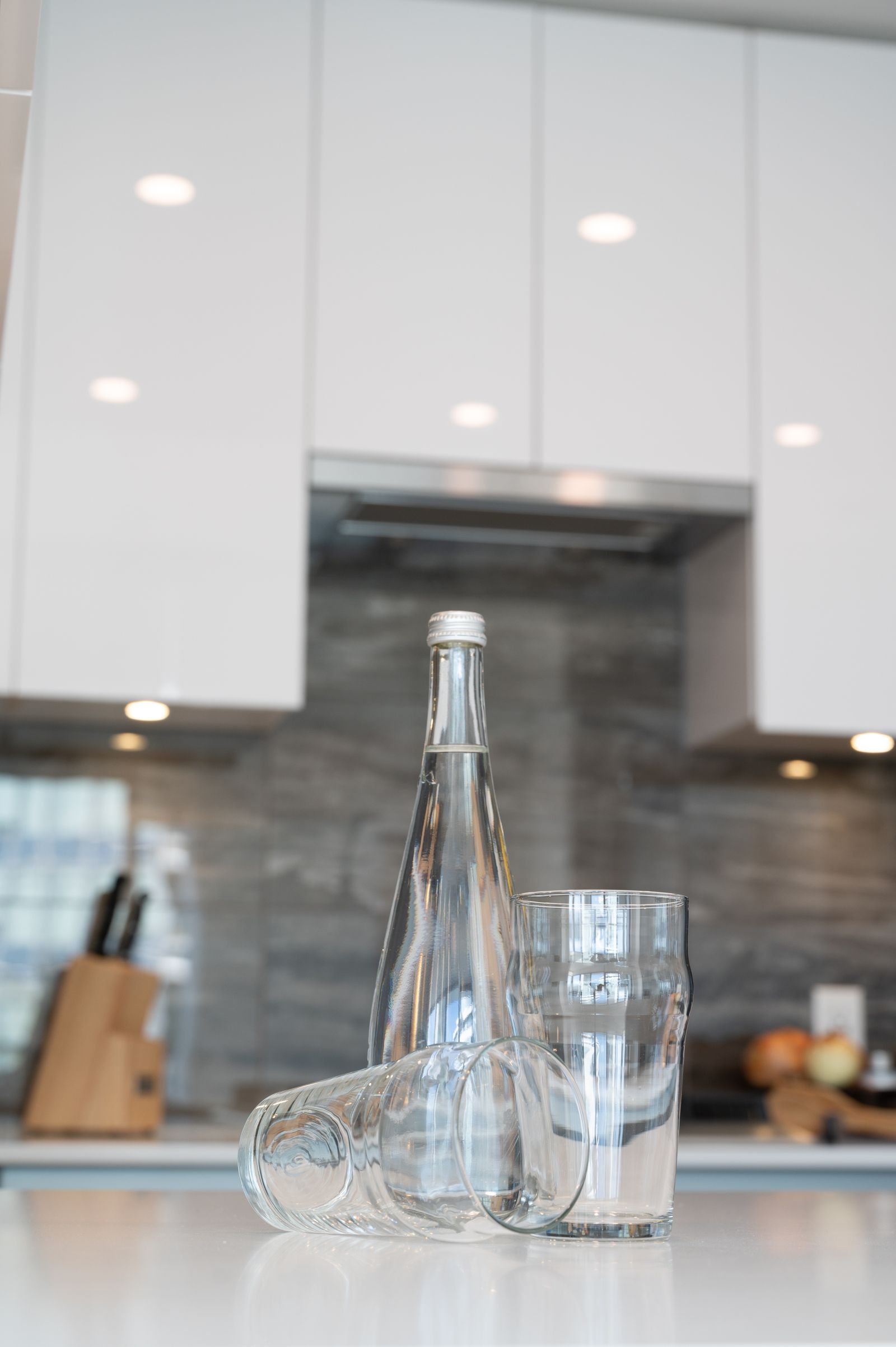 Glass bottle and drinking glasses arranged in a kitchen setting