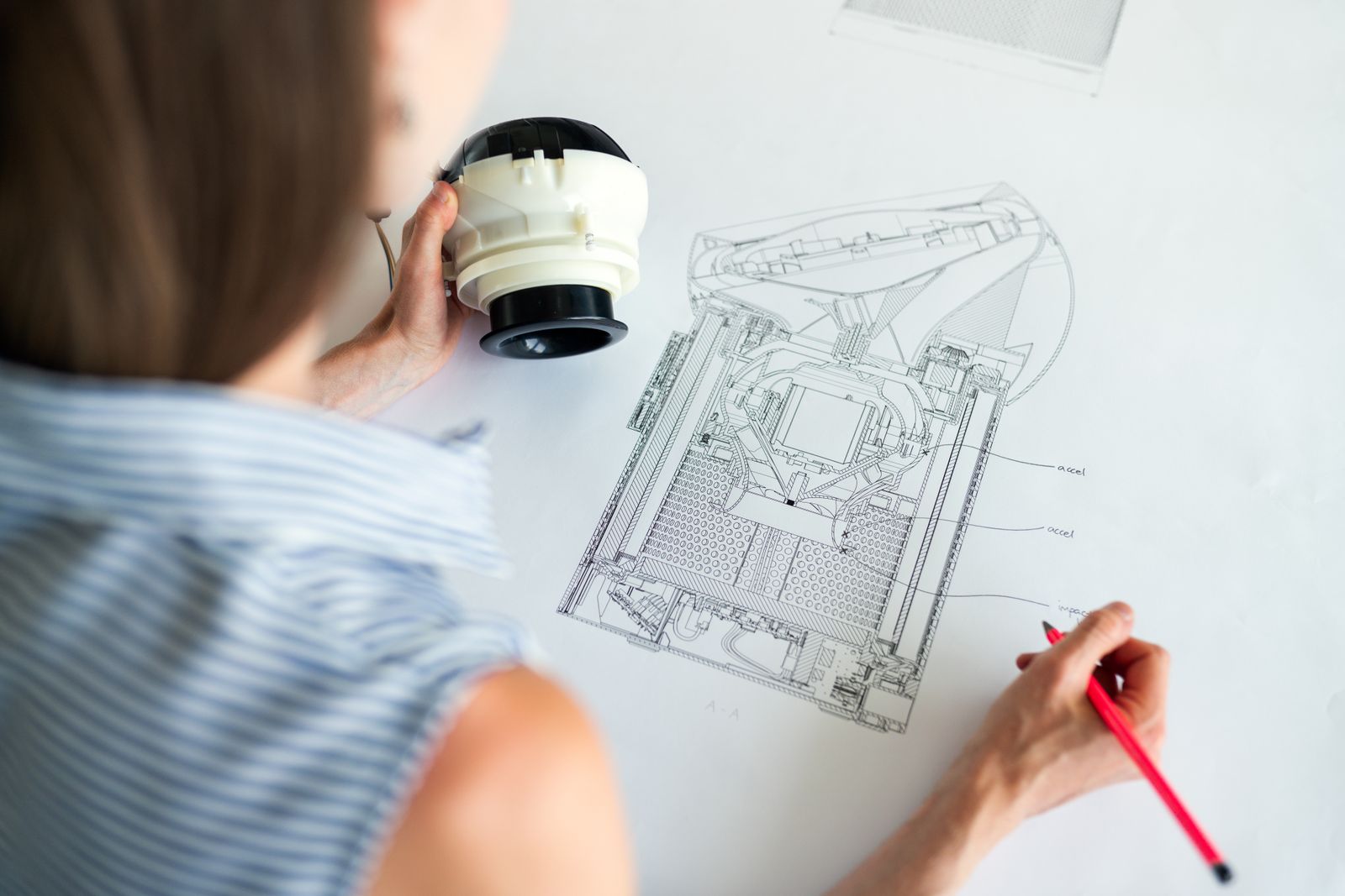 Engineer compares a physical component with a detailed sectional technical drawing